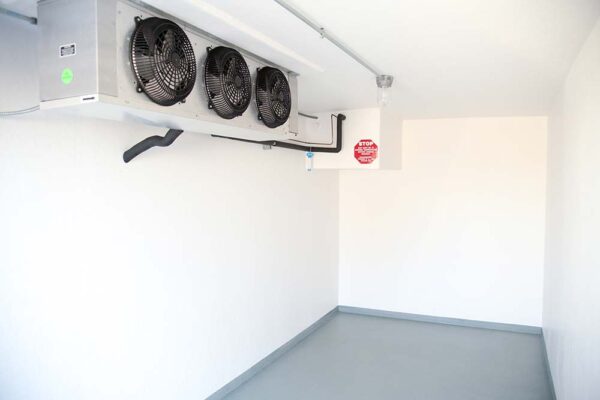 Inside of a Polar King small refrigerated trailer with white walls and three black fans