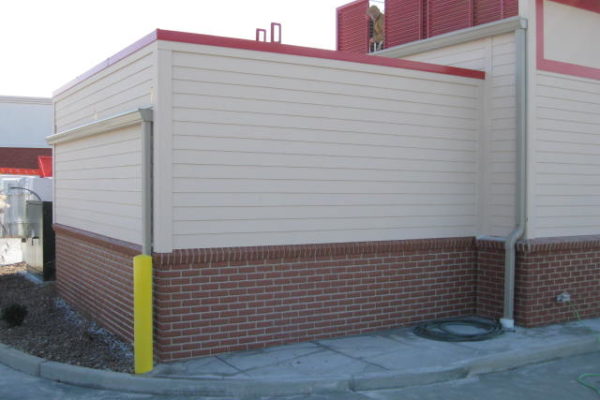 Commercial cooler unit with white side panels, red trim, and brick at the bottom